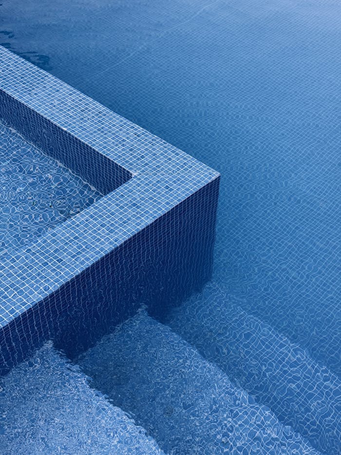 Abstract image of blue tiled pool edges with water ripples, exuding a minimalist and calming vibe.